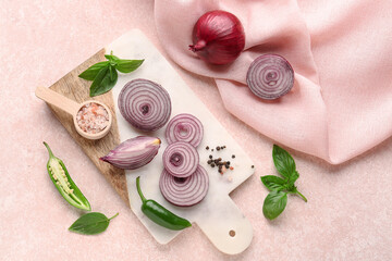 Board with fresh onion slices, jalapeno and spices on pink background