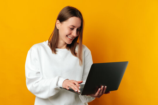 Young smiling confident woman is working at the laptop she is holding.