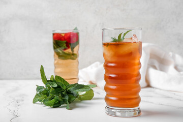 Glasses of ice tea with orange and strawberry on white background