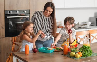 Mother packing school lunch for her little children in kitchen