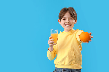 Little boy with orange and glass of juice on blue background