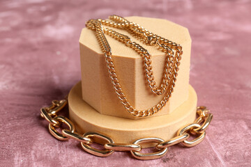 Decorative podiums with beautiful chain necklace and bracelet on pink background