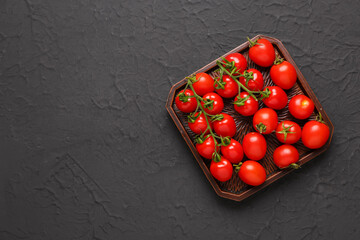 Tray with fresh cherry tomatoes on black background