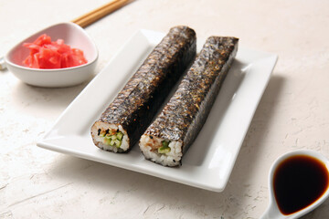 Plate with tasty maki rolls, ginger and soy sauce on light background