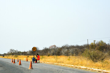 Workers of the repair crew sit on the side of the road near the road closure to repair the road.