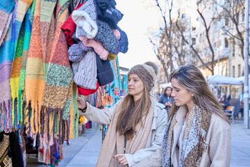 two friends shopping for clothes at a street stall