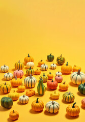 Pumpkins arranged in different color patterns on a pastel yellow background. Thanksgiving holiday concept. Copy space.