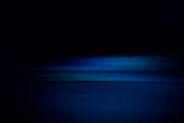 Neon blue motion light trails over black background. Abstract speed effect. Rays of light moving fast over dark background