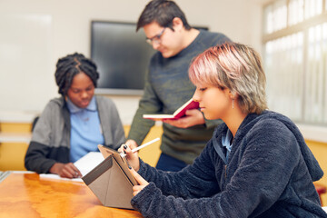 Latin American teenage students in class studying with the teacher supporting them