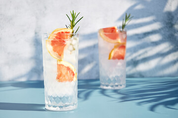 Summer chilled grapefruit cocktail with ice and rosemary sprig. Summer cold drinks. Soda with citrus