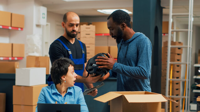 Small business owners doing quality control before shipping order to customers, looking at products in boxes. Three people working in warehouse and packing merchandise, shipment.