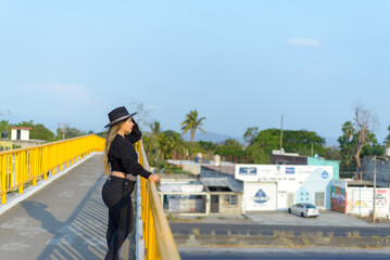 Fototapeta premium Portrait of young woman with positive attitude on a pedestrian bridge. Sunset with blue sky.