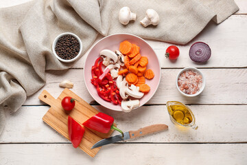 Bowl with fresh vegetables on light wooden background