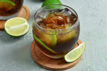 Glass of cold Cuba Libre cocktail on grey background