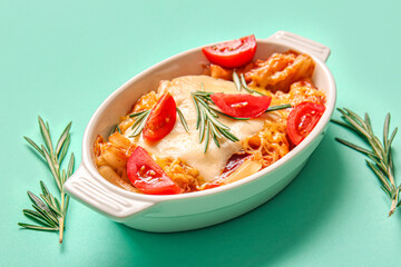 Baking dish of pasta with tomato sauce and cheese on blue background