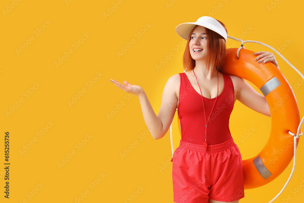 Wall mural Female lifeguard with ring buoy showing something on yellow background