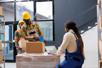 African american man and woman order pickers working in retail warehouse. Package handler packing cardboard box with adhesive tape dispenser while storehouse manager checking pick ticket on laptop