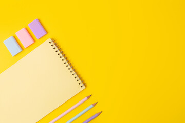 Top view of yellow notebook and stationery in pastel colors,negative spacr for text.