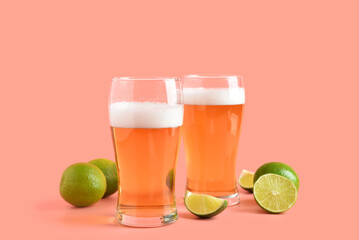 Glasses of cold beer with lime on pink background