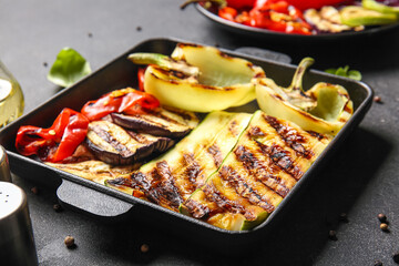 Baking dish with tasty grilled vegetables on black background
