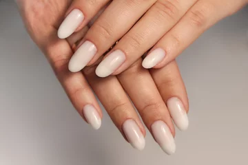 Rolgordijnen Nude manicure. Long almond shaped nails. Nail design. Manicure with gel polish. Close-up of the hands of a young woman with a gentle nude manicure on her nails. Bright nails with gel polish. © Alina