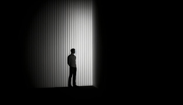 Dark empty room with the silhouette of a man standing alone. Based on Generative Ai.