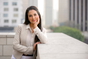 A young beautiful brunette business woman portrait headshot, casual smile outside financial district downtown buildings skyline in background - 615259748