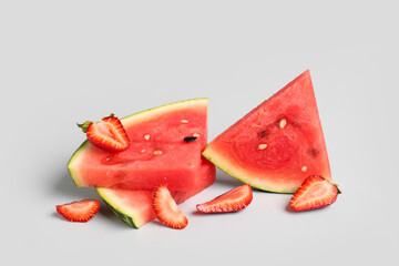 Pieces of fresh watermelon and strawberries on grey background