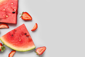 Pieces of fresh watermelon and strawberries on grey background