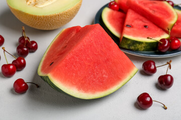 Plate with pieces of fresh watermelon, cherries and melon on grey background