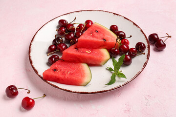 Pieces of fresh watermelon and cherries on pink background