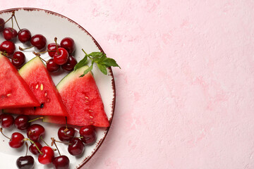 Pieces of fresh watermelon and cherries on pink background