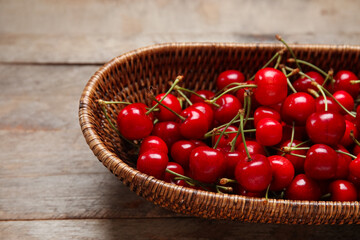 Wicker bowl with sweet cherries on grey wooden background