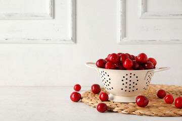 Colander with sweet cherries on white background