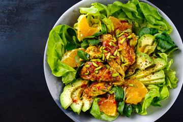 Traditional German iceberg and lambs lettuce served with chicken, avocado and orange slices with spicy sweet and sour curry sauce served as close-up on a design plate with text space left