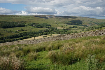 Fototapeta na wymiar Drystone Walls, Barns and the Village of Gunnerside in Swaledale, The Yorkshire Dales, North Yorkshire, England