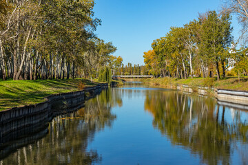 Fototapeta premium Lake in the city garden with an iron bridge on an autumn sunny day with a clear cloudless sky
