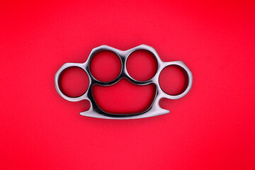 Silver Brass Knuckles Layed Down. Isolated on Red Background