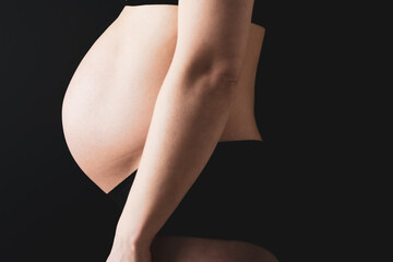 Side view of naked round belly of pregnant woman in underwear during last pregnancy month. Last month of pregnancy - week 36. Cropped. Black background.