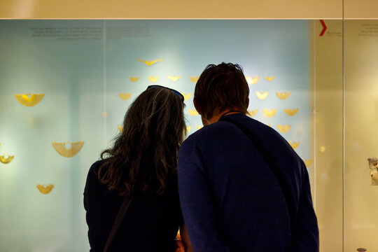 Bogota, Colombia - January 3, 2023: Couple of visitors look at the Zenu earmuffs in the Gold Museum