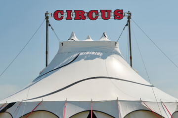 Small white circus tent with red characters against a blue sky.
