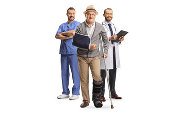 Full length portrait of a senior male patient with a crutch and doctors standing in the back