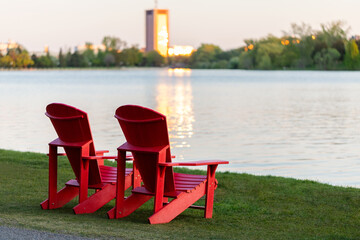 Adirondack red chairs by lake shore in Ottawa, Canada. Peacefull evening scene.
