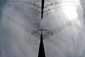 Wide angle view up at two electrical transmission towers in silhouette 