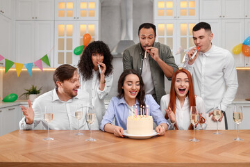 Happy friends with tasty cake celebrating birthday in kitchen