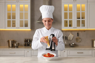 Professional chef grating cheese into delicious dish at white marble table in kitchen