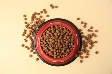 Dry dog food and feeding bowl on beige background, flat lay