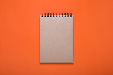 New office notebook on orange background, top view
