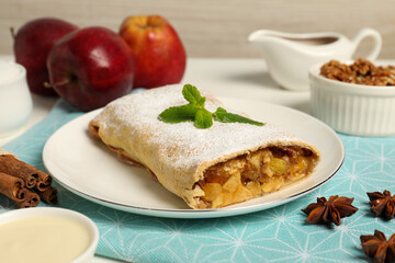 Delicious strudel with apples, nuts and raisins on table, closeup