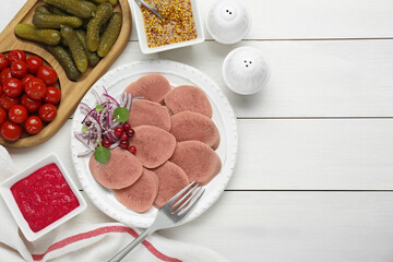 Tasty beef tongue pieces, berries, red onion and ingredients on white wooden table, flat lay. Space for text